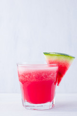 Watermelon drink in glasses with slices of watermelon. Watermelon smoothies on white background. Summer healthy drink for vegetarian. Copy space