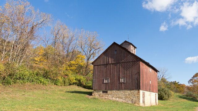 old red barn on a hillside in fall