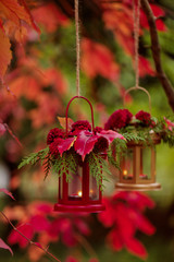 Fall time. Autumn decoration. Candlesticks in the form of lanterns with daisy decor, juniper and autumn red leaves.
