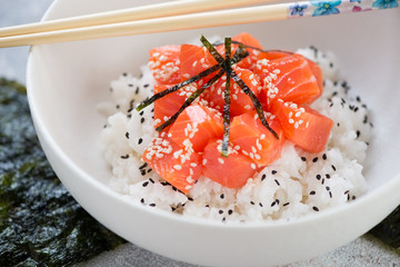 Poke with salmon served in a white bowl, selective focus, closeup, studio shot