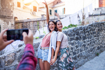 Two female friends photographed by friend on smartphone