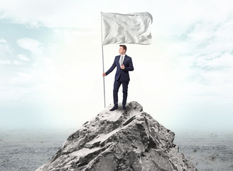 Obraz premium Handsome businessman on the top of the mountain with white flag