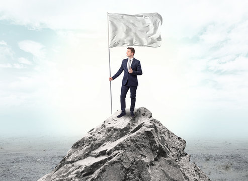 Handsome businessman on the top of the mountain with white flag