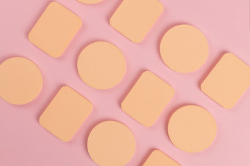 A lot of sponge, a beautiful blender for applying foundation or powder. Flat lay on a pink background, copy space.