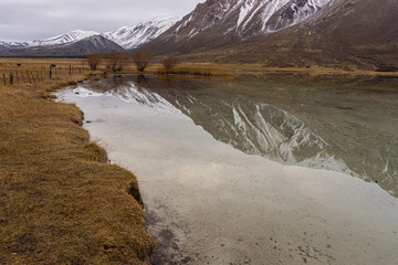Scene view of snow-capped mountains reflected on water near lagoon shore in Patagonia, Esquel, Argentina