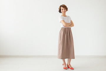 people, fashion and style concept - young woman posing in clothes in studio on white background.