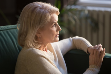 Pensive elderly woman look in distance thinking or mourning