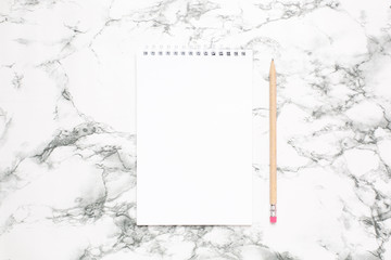 White notebook and pencil on a marble background