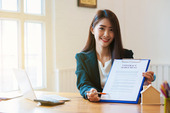 Businesswoman holding contract And use the pen to point to the contract.