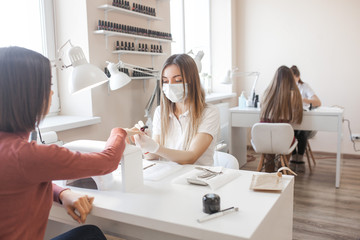 Manicurist making a manicure in the salon. Master servising her client. Nails care procedure.