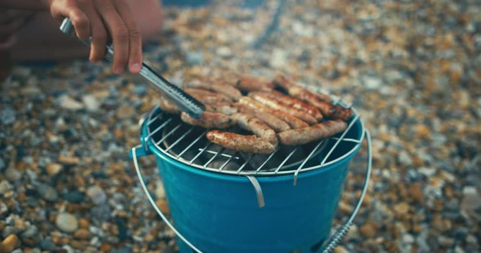 Young woman barbecuing sausages on the beach
