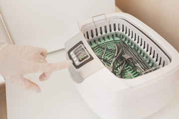 Manicurist sterilize her tools in the autoclave or oven. Master int he salon preparing her...