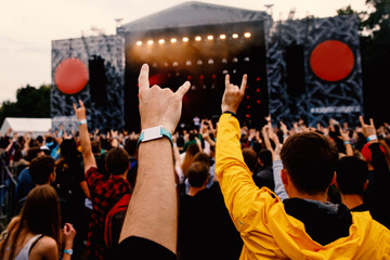 Hands of music funs formed in a goat sign. Outdoor concert show.