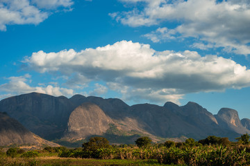 A mountain range rises up over lush green vegetation in Mozambique, Africa