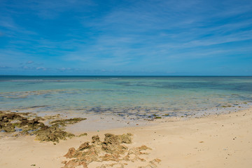 An empty white beach and shallow turquoise water under a sunny blue sky on the Island of Mozambique...