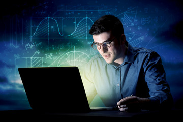 Young handsome businessman working late at night in the office with blue mathematic charts in the background