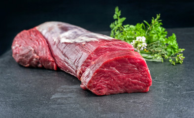 Dry aged Rinderfilet Medaillons Steak natur mit einem Bouquet Garni als closeup auf schwarzen Hintergrund mit Textfreiraum