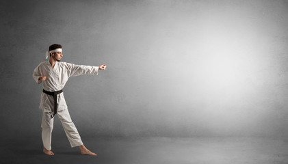 Small karate man fighting in an empty grey copy space