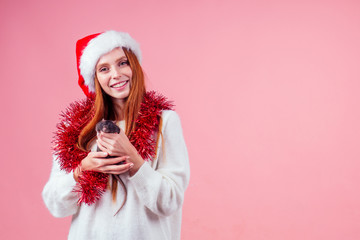 redhaired ginger girl in red santa hat and tinsel hugging cute black male rat in studio gray...