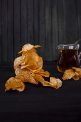 Tasty chips with olive oil on black background