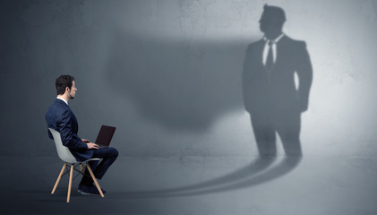 Humble businessman staying and offering stuffs to a huge angry bull shadow