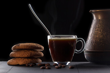 glass of coffee with oatmeal cookies on a black background