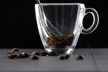 glass cup with a teaspoon of coffee on a black background