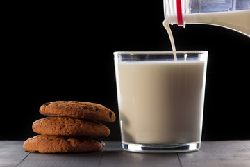 Milk with cookies on a black background