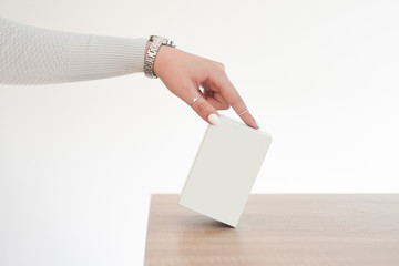 A elegant woman hand holds light blue box on a wooden table. Perfume present for her. Mock up. 