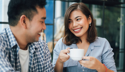 Asian woman in blue shirt  in cafe drinking coffee and talking with boy friend smile and happy face