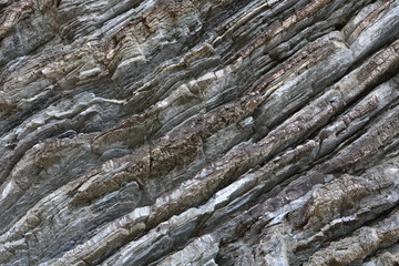 Background on the basis of the texture of rock. Gray-brown stone texture with inclined weathered stripes