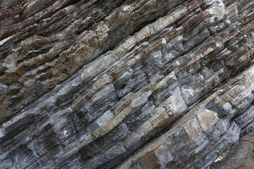 Background on the basis of the texture of rock. Gray-brown stone texture with inclined weathered stripes