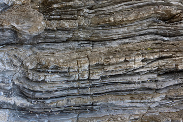 Background on the basis of the texture of rock. Blue-brown stone texture with horizontally weathered stripes