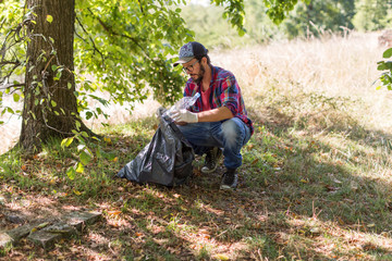 Obraz premium Young man picking up litter in his local park