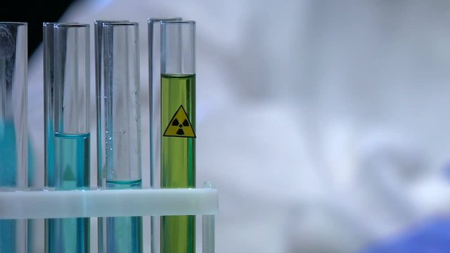 Scientist putting radioactive liquid in tube rack, weapons of mass destruction