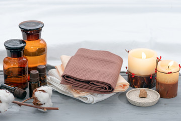 Aromatherapy oil bottles, burning candles and towels on a wooden floor background.