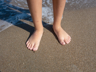 female feet (seashore) on wet sand background