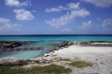 Ocean blue sky with white clouds and a barrier