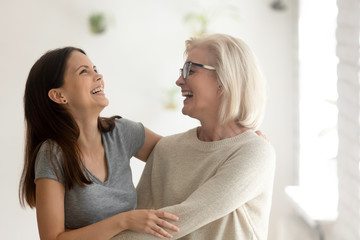 Happy aged mother and millennial daughter have fun laughing