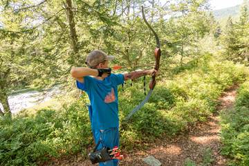 boy with cap and blue shirt shooting bow