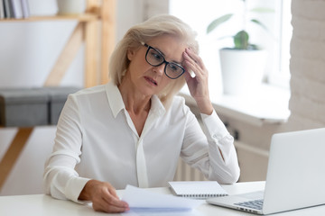 Pensive senior woman thinking of problem solution in office