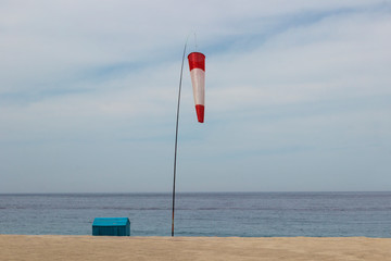 windsock on the seashore, small house, yellow sand, blue sky
