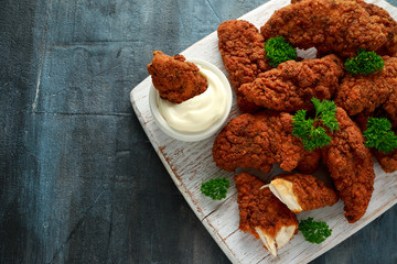 Breaded chicken strips with mayonnaise on white wooden board