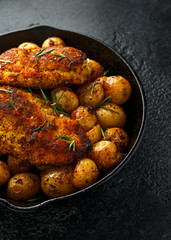 Freshly cooked breaded chicken Kiev's served with crispy baked rosemary potato in rustic cast iron skillet, pan