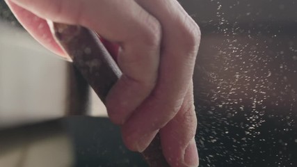 Slow motion woodworker hand sanding walnut board with sand block