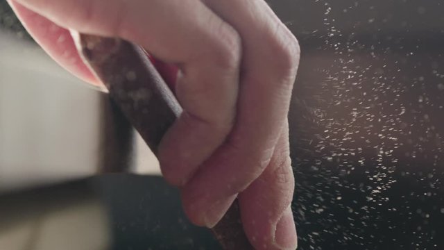 Slow motion woodworker hand sanding walnut board with sand block