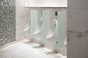 White ceramic urinals with the automatic flush system in the public toilet in a shopping mall.