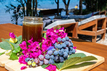 Natural honey guttering into the pot on a table with grapes