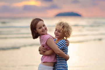 Child playing on ocean beach. Kid at sunset sea.