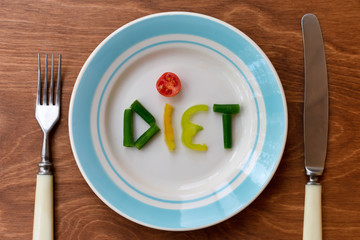 Plate with word "diet" made of vegetables. Concept of hard dieting and weight loss.